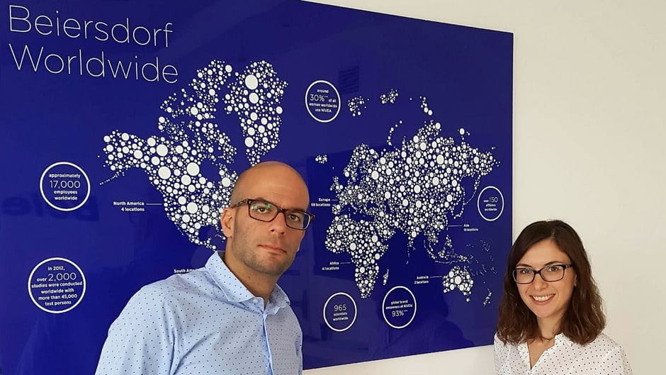 Two Beiersdorf Greece employees in front of Beiersdorf worldwide map