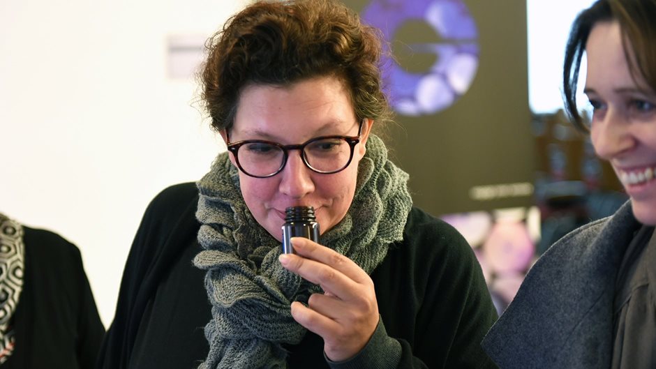 woman smelling on one fragrance bottle