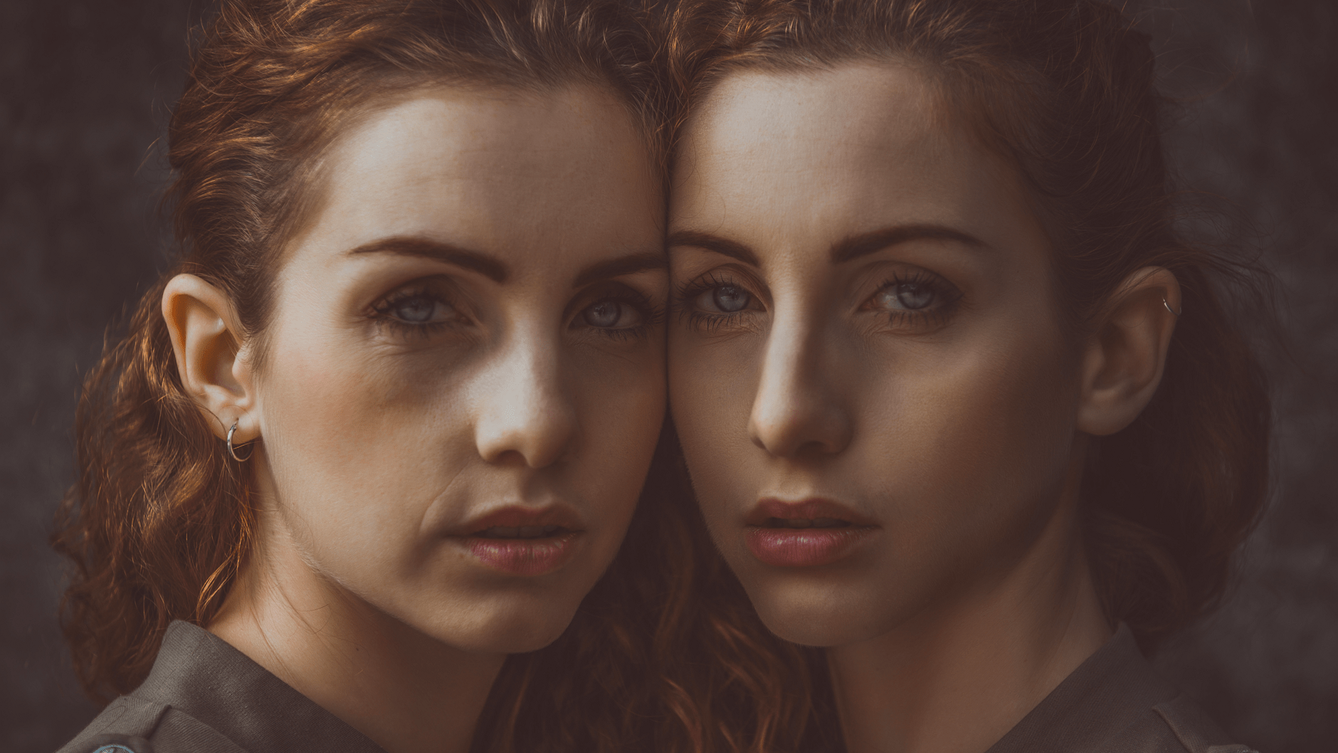 Close-up portrait of two women with similar features standing side by side, looking directly at the camera with calm, neutral expressions.