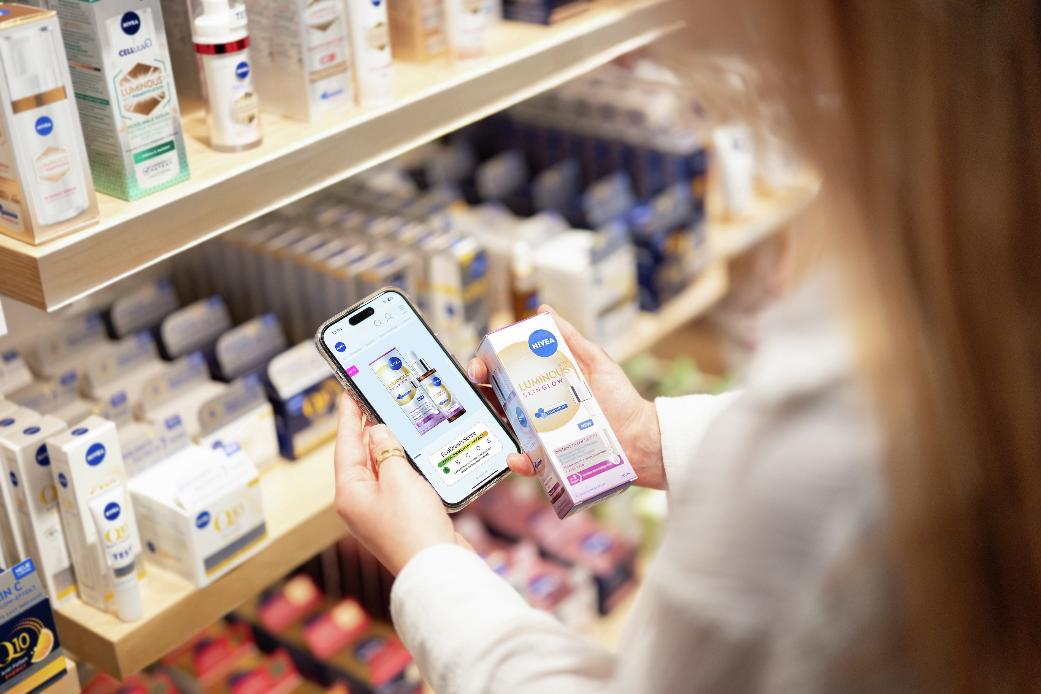 Woman with long hair holding a smartphone showing the EcoBeautyScore of a NIVEA product