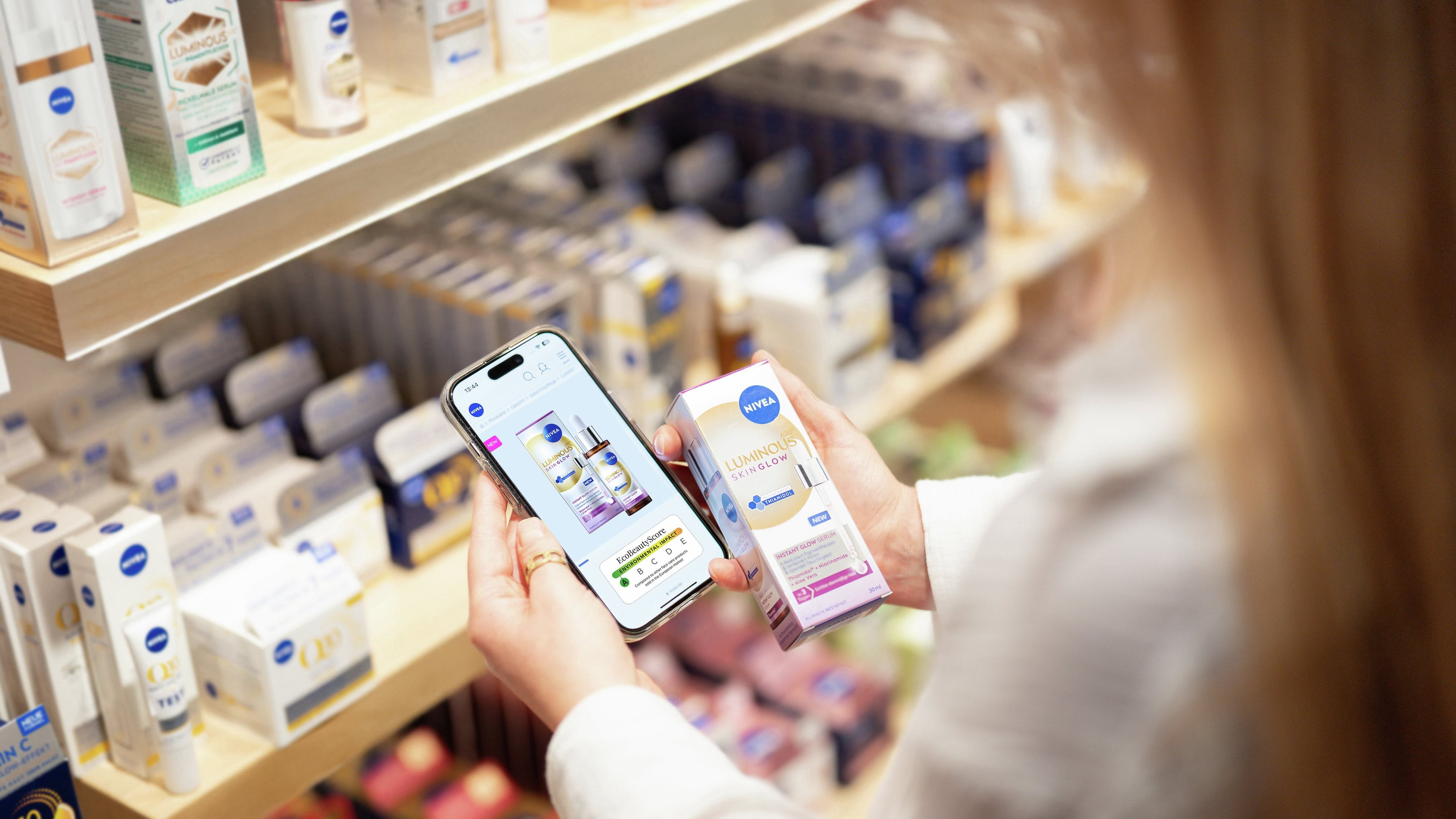 Woman with long hair holding a smartphone showing the EcoBeautyScore of a NIVEA product