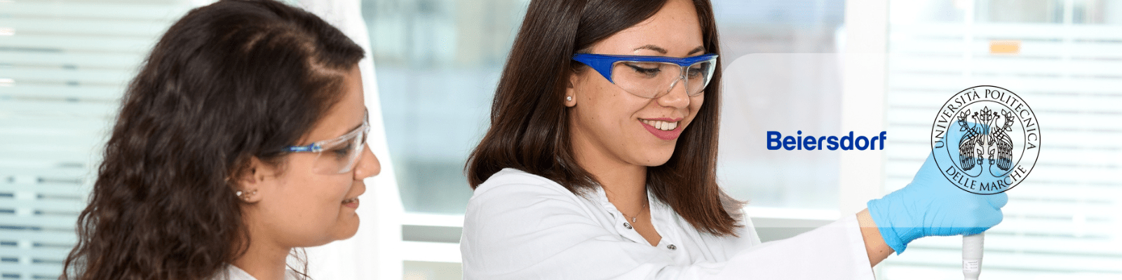 Two scientists in a laboratory reviewing information together, with one holding a transparent digital-style interface element in a research setting.