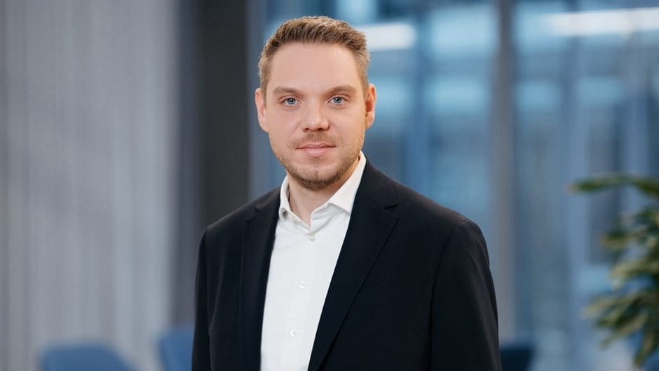 Person in a suit standing in front of a window.