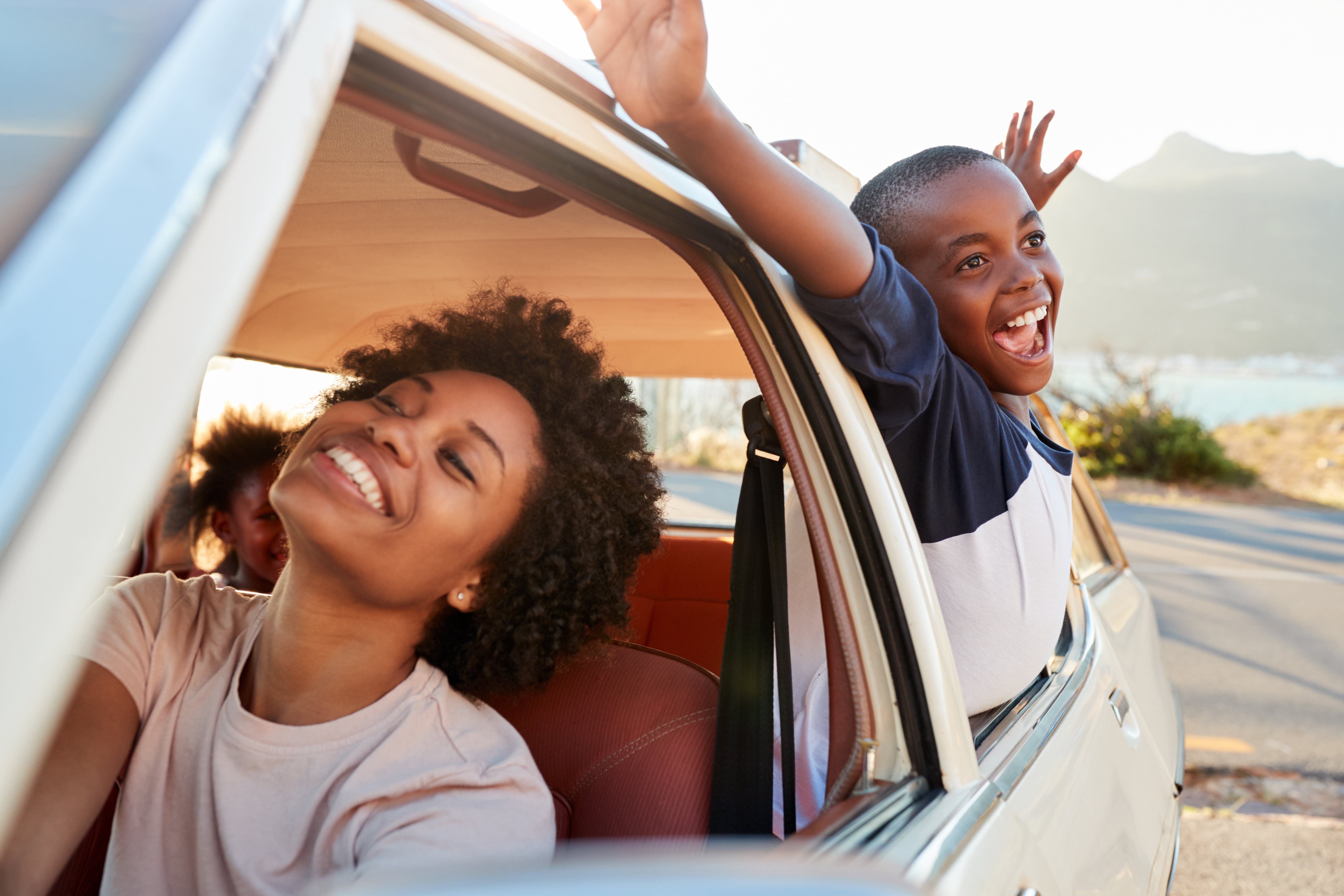 woman driving with child happy stretching out the window