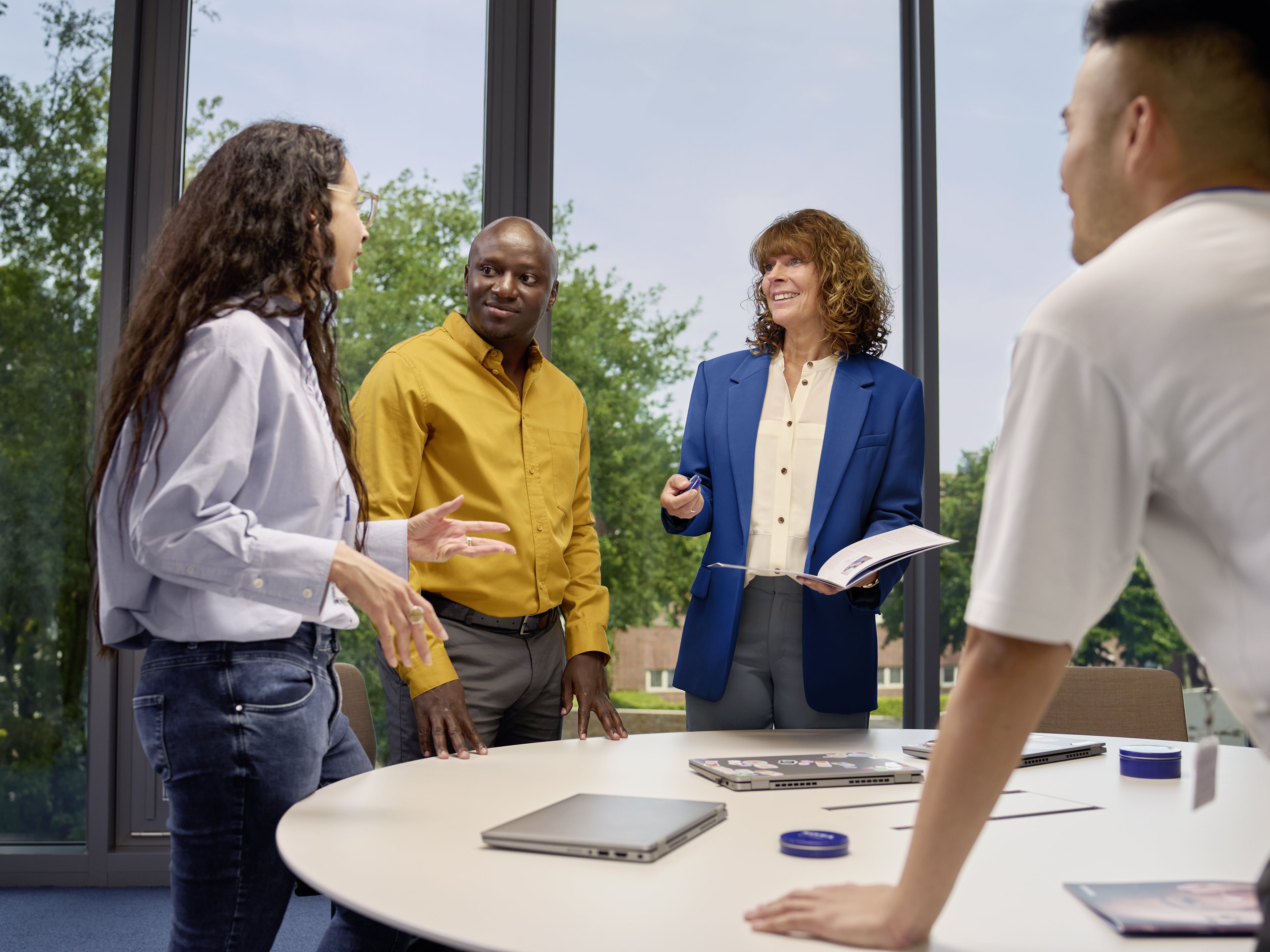 A group of male and female colleagues talking in a bright conference room.