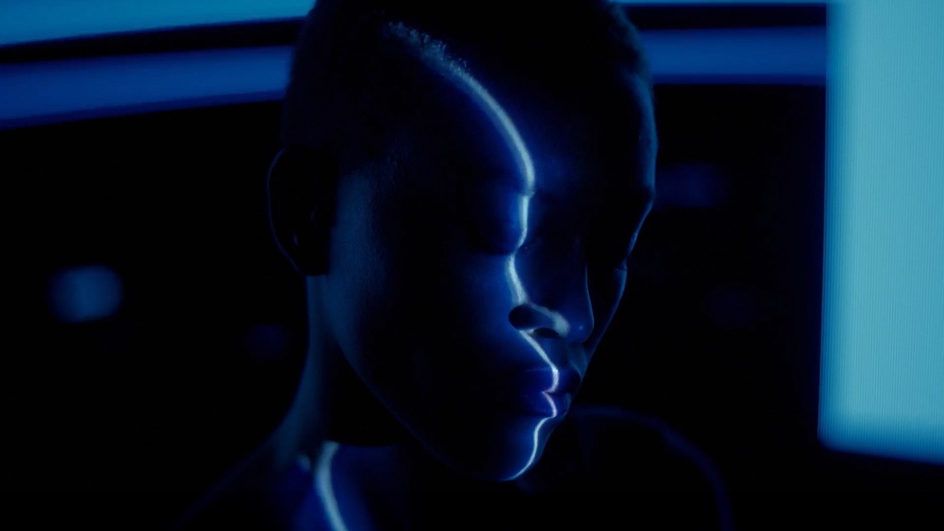 Abstract close-up of a human face in blue light, highlighting skin contours and texture in a stylized, futuristic visual.