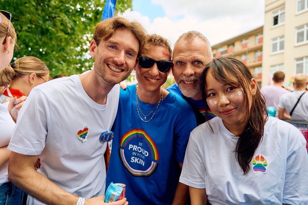 Colleagues at a Pride event wearing rainbow badges and shirts, showing support for LGBTIQ+ inclusion.