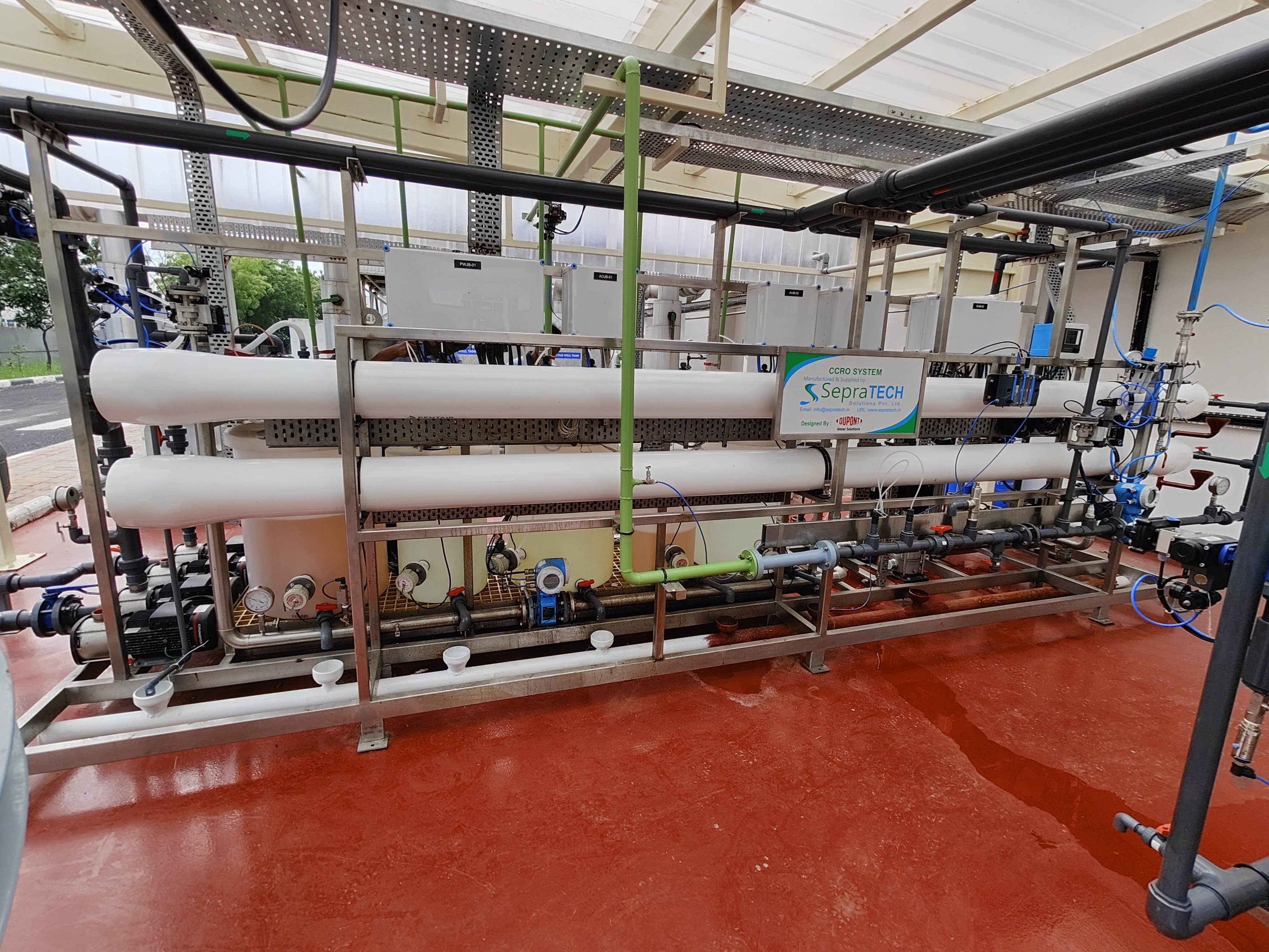 Industrial reverse osmosis water treatment system with horizontal membrane vessels, pipes, valves, gauges, and control panels mounted on a metal frame inside a processing facility.
