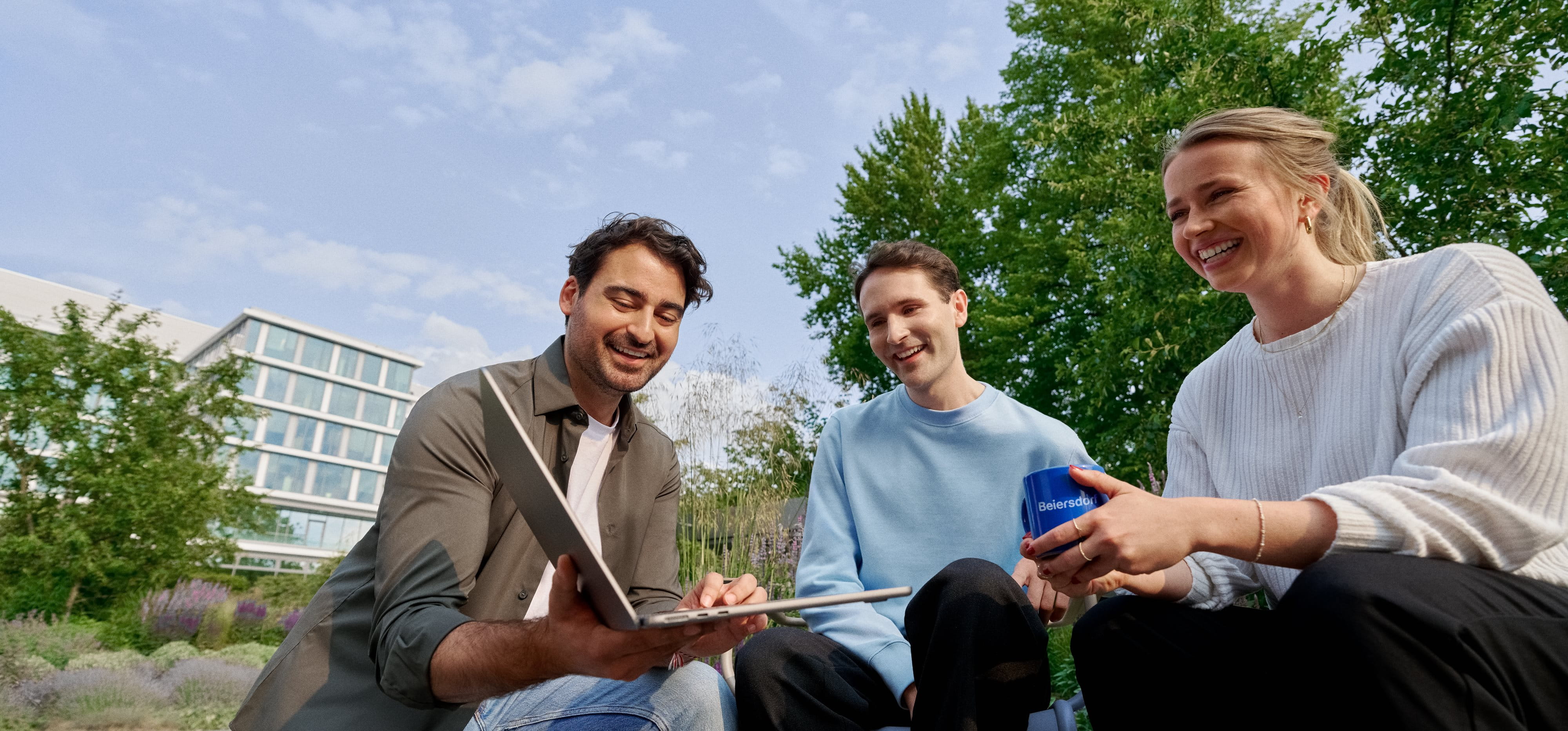 Beiersdorf employees collaborating outdoors on a shared project, demonstrating teamwork, flexibility and a modern work environment.