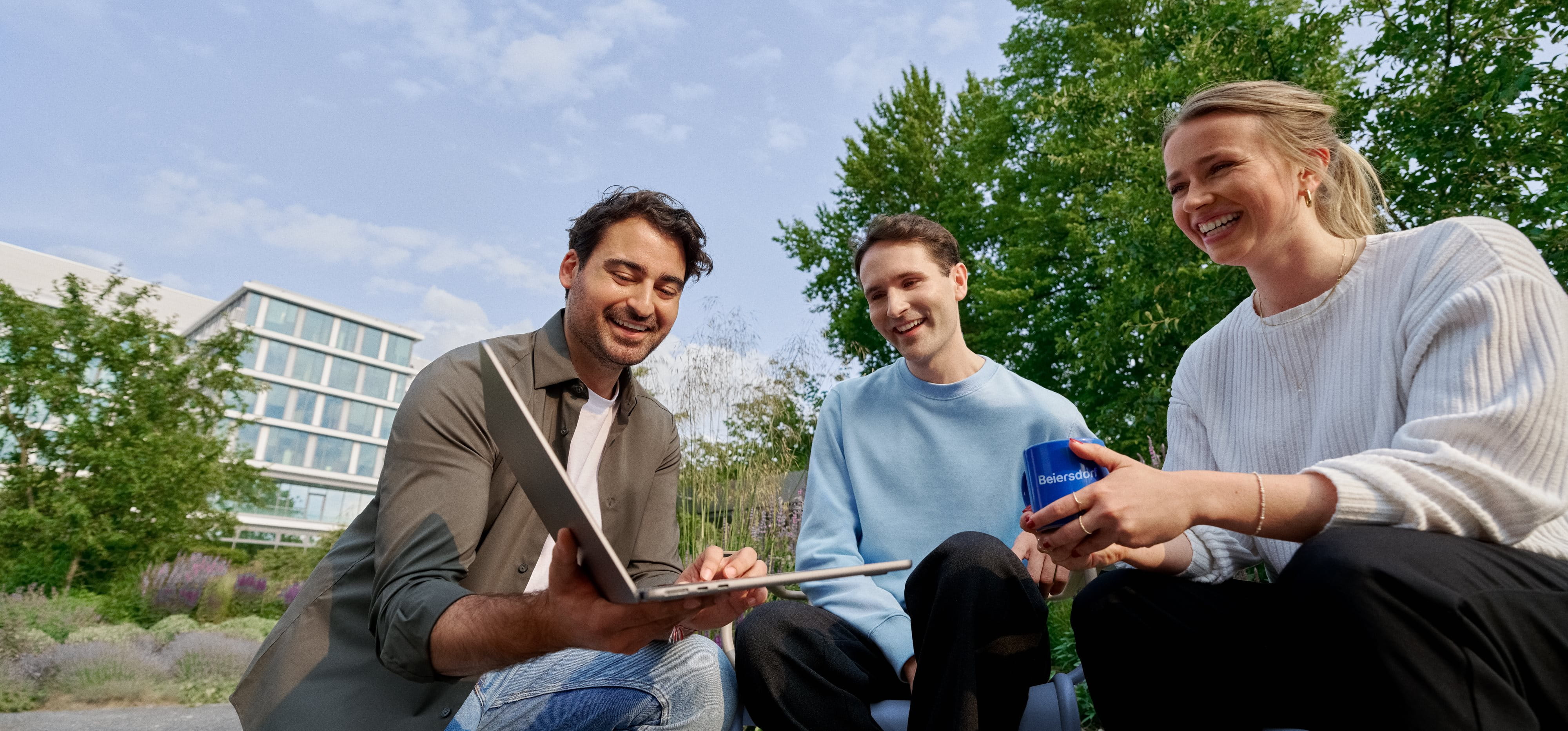 Beiersdorf employees collaborating outdoors on a shared project, demonstrating teamwork, flexibility and a modern work environment.