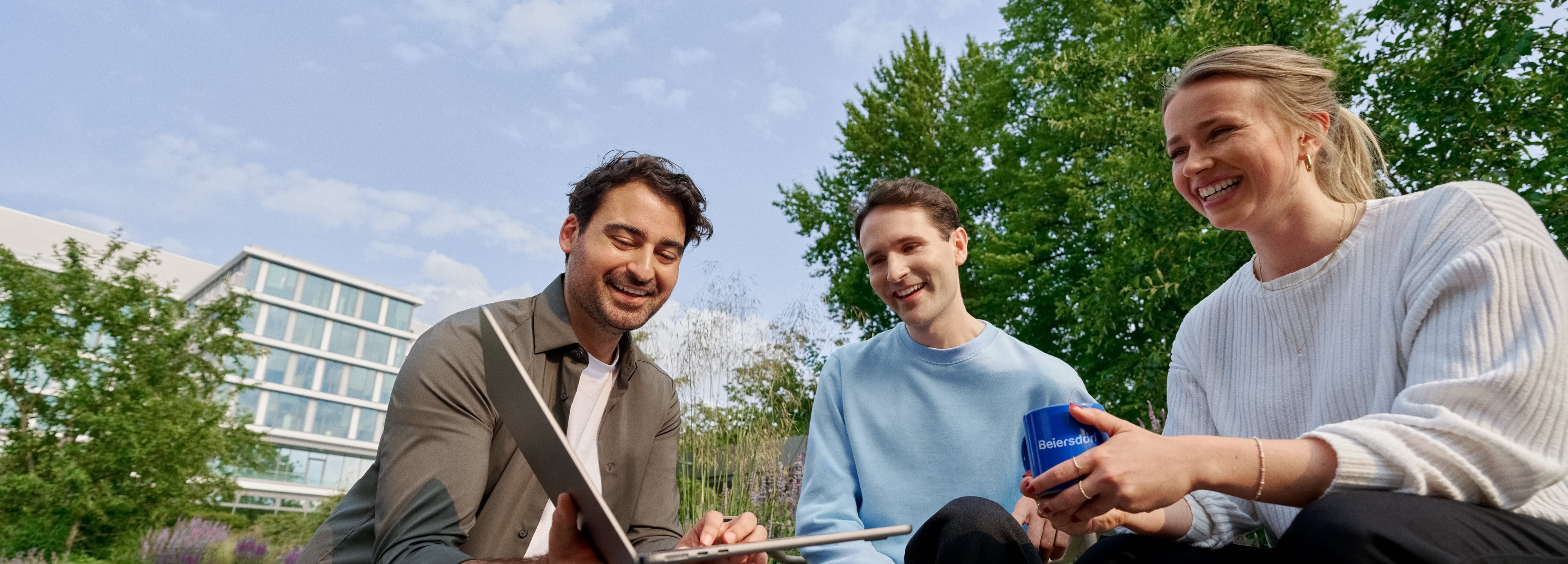 Beiersdorf employees collaborating outdoors on a shared project, demonstrating teamwork, flexibility and a modern work environment.