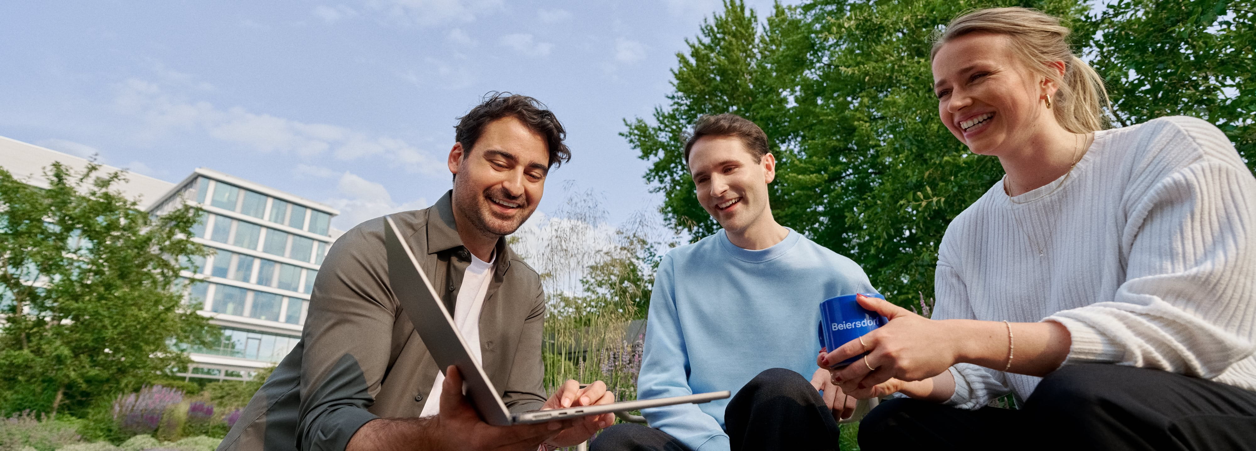 Beiersdorf employees collaborating outdoors on a shared project, demonstrating teamwork, flexibility and a modern work environment.