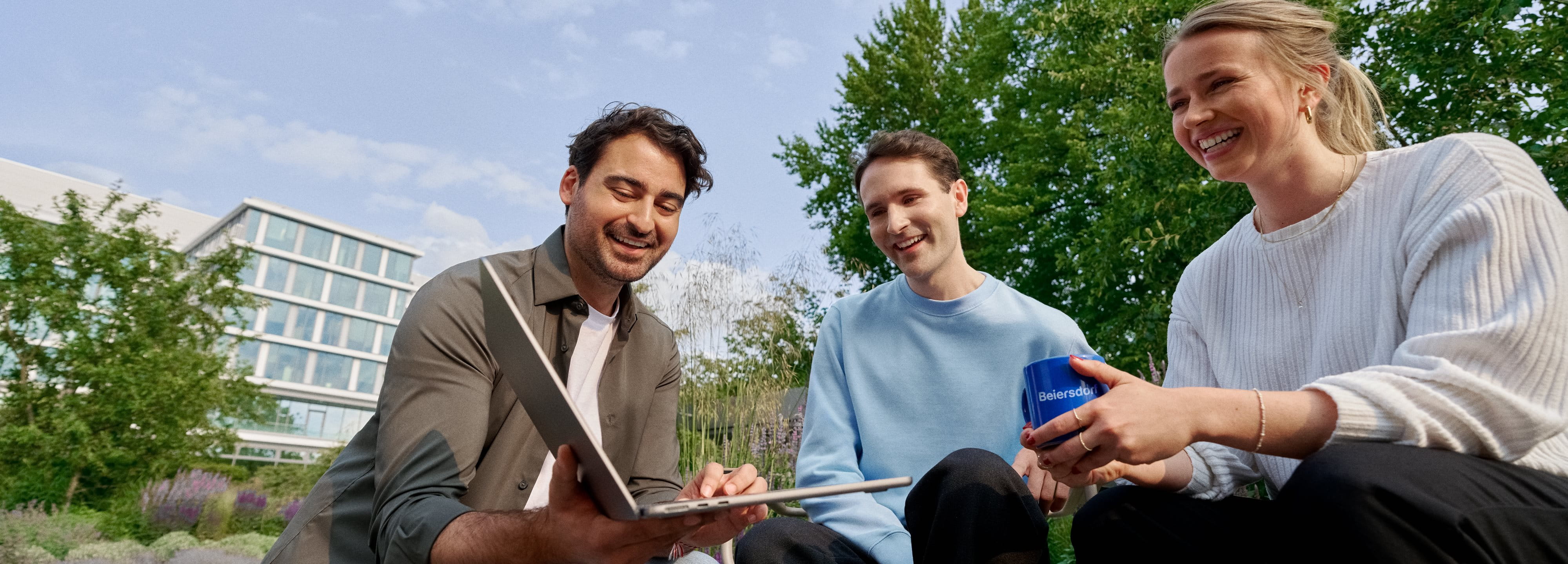 Beiersdorf employees collaborating outdoors on a shared project, demonstrating teamwork, flexibility and a modern work environment.
