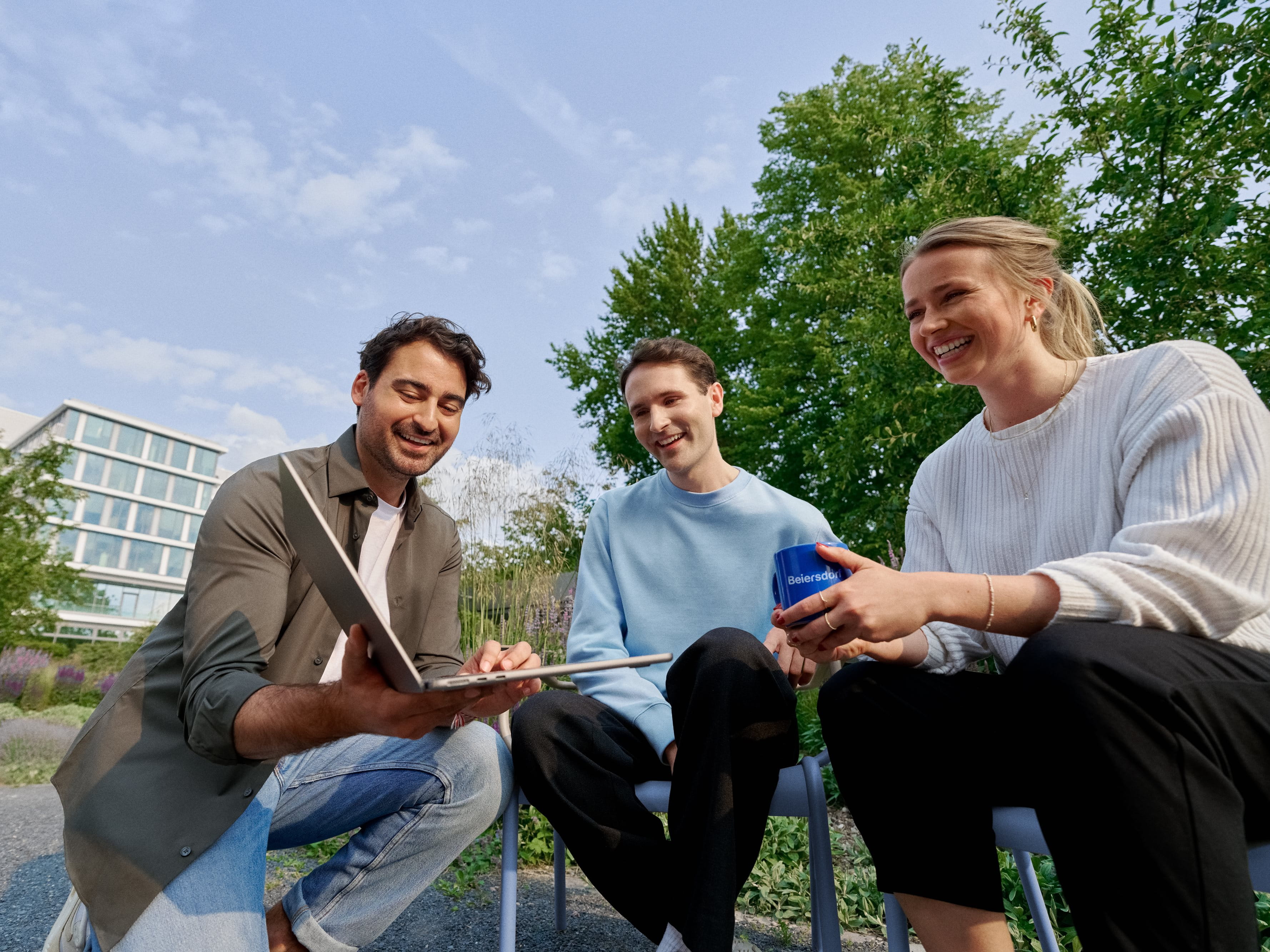 Beiersdorf employees collaborating outdoors on a shared project, demonstrating teamwork, flexibility and a modern work environment.