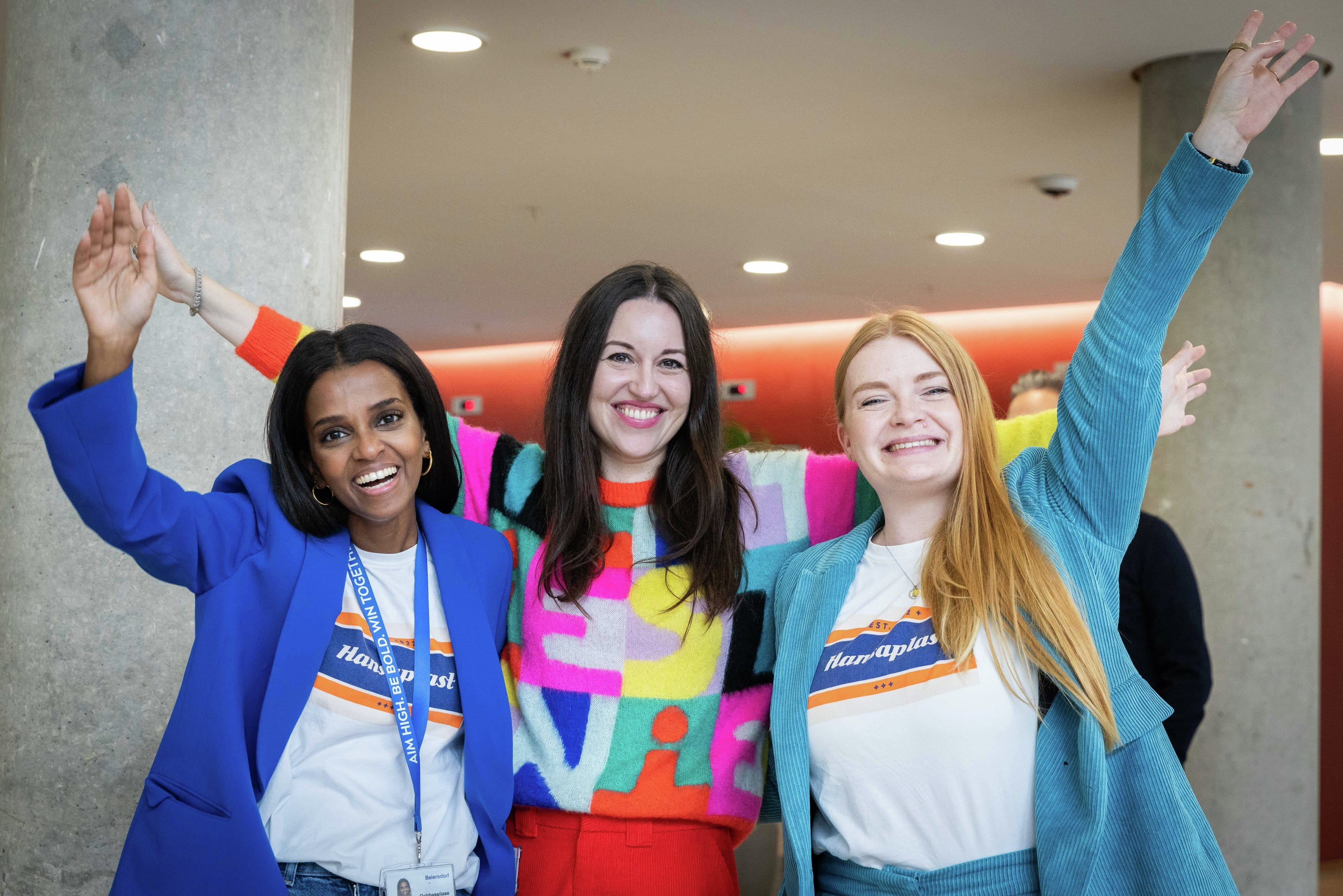 Three colleagues cheering and smiling into the camera.