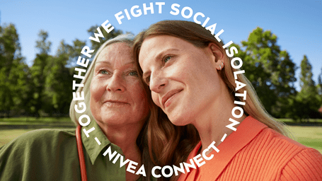 Two women leaning close together outdoors, smiling softly, with circular text overlay reading ‘Together we fight social isolation – NIVEA Connect’.