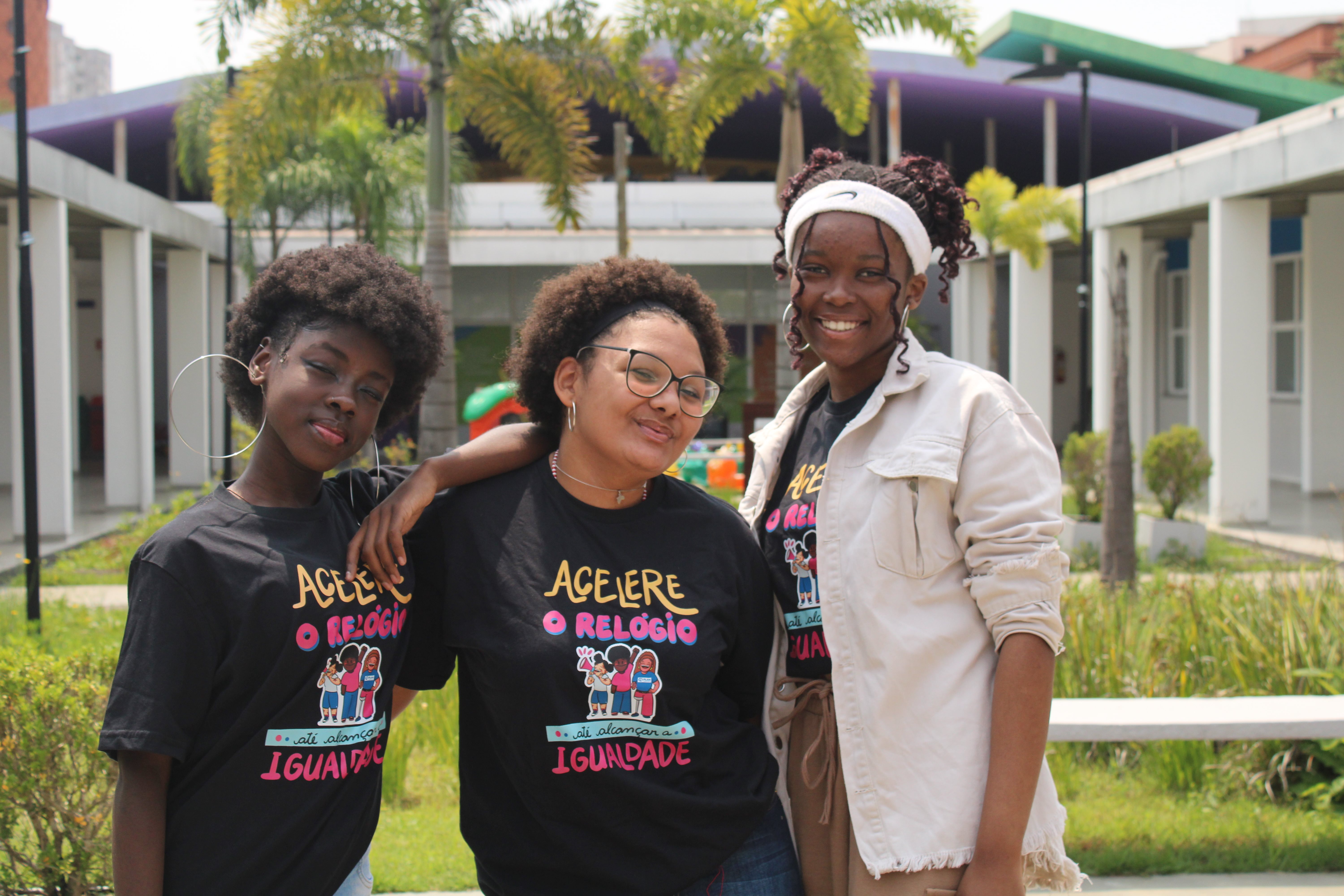 Three girls standing next to each other closely, smiling into the camera