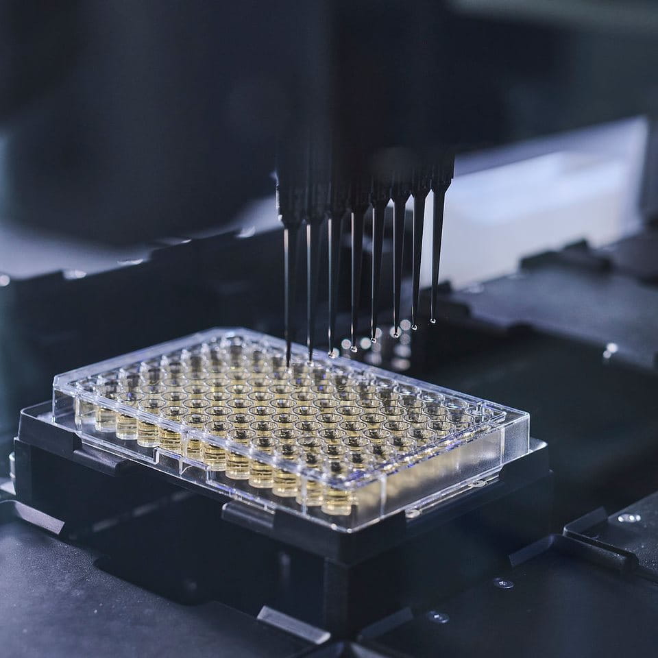 Automated laboratory pipetting system dispensing liquid into a multiwell plate, illustrating high-throughput scientific testing and analysis.