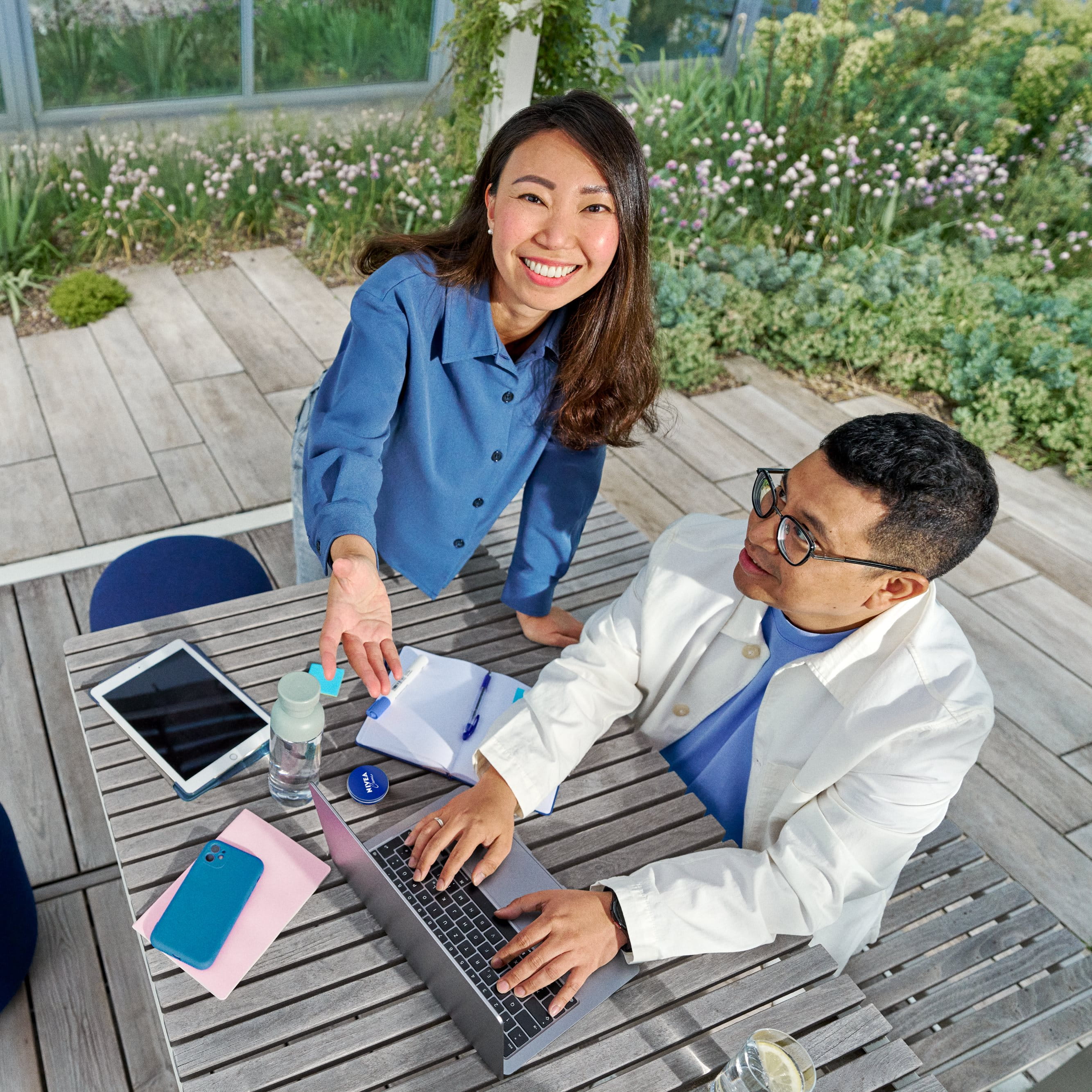 Three people standing outdoors near a modern building, smiling and laughing together in casual clothing.