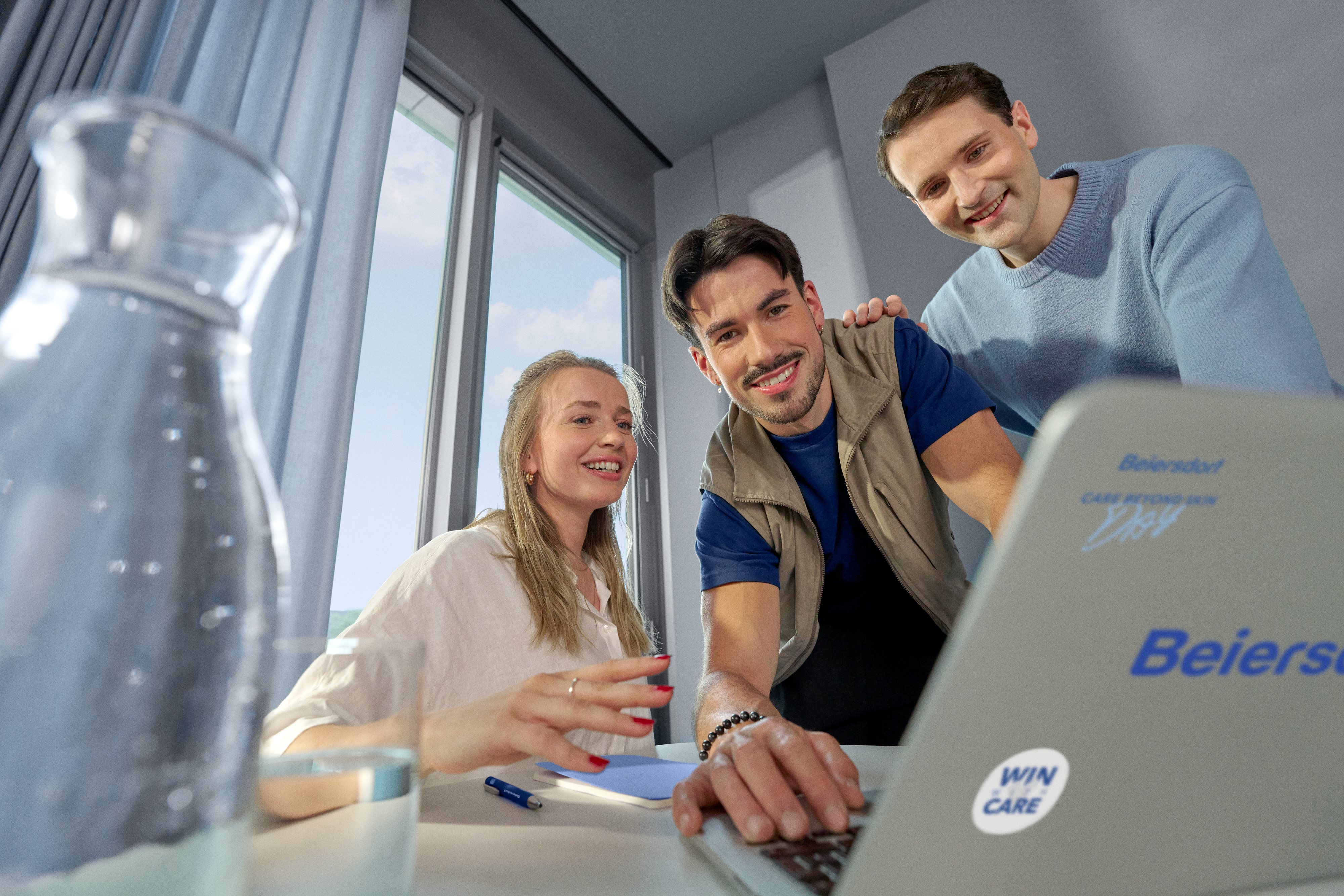 Beiersdorf employees reviewing project work on a laptop, highlighting collaboration, innovation and career opportunities within a global team.