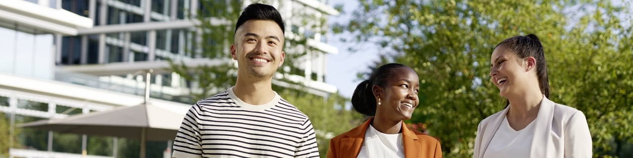 Three young people are looking at each other and smiling